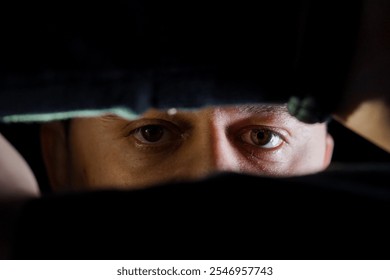 Intense Gaze: A Close-Up of a Man's Eyes Emerging from Shadows. - Powered by Shutterstock