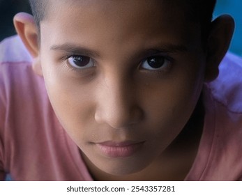 Intense Gaze Portrait of a Child. A striking close-up portrait of a child with an intense, focused gaze. The soft lighting highlights the child's expressive eyes and thoughtful expression. - Powered by Shutterstock