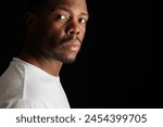 Intense gaze of a young African American man on dark background