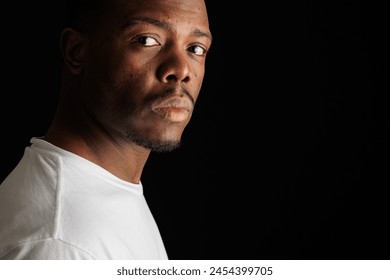 Intense gaze of a young African American man on dark background - Powered by Shutterstock