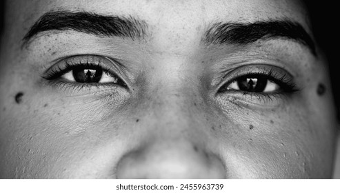 Intense macro close-up face of one young black woman facial eyesight features in monochrome, black and white gaze at camera - Powered by Shutterstock