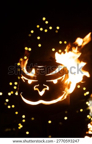 Intense Orange Flame Inside a Devilish Mask Decoration at Night.
