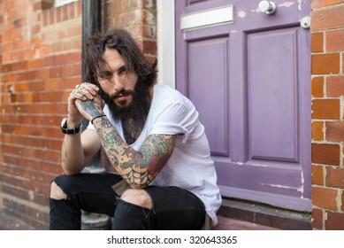 Intense portrait of young tattooed man sit on the street in Shoreditch borough. London, UK. Hipster style - Powered by Shutterstock