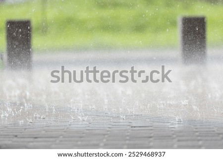 Intense rainfall drenches the cobblestone path, causing water to splash in all directions. Puddles form as drops create ripples, enhancing the tranquil atmosphere.