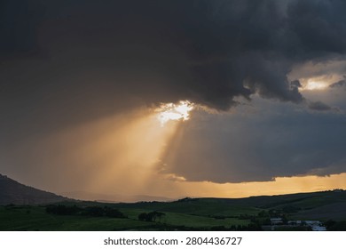 An intense sunset with light illuminating the cloudy sky over a typical Tuscan landscape of green hills and cypress trees, siena, tuscany