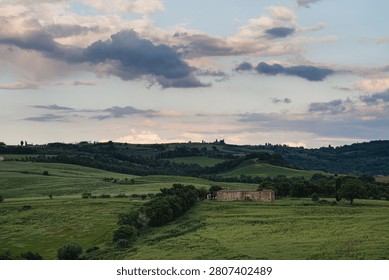 An intense sunset with light illuminating the cloudy sky over a typical Tuscan landscape of green hills and cypress trees, siena, tuscany