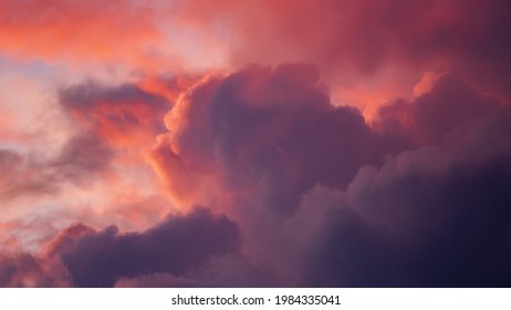 Intense vibrant dramatic cloudscape scenery with clouds lit up in various shades of contrasting pink and magenta against at blazing sunset 
