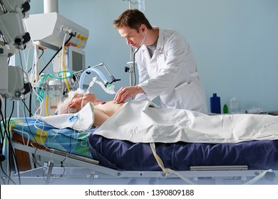 Intensive care caucasian doctor examines intubated critical stance patient in intensive care department. Doctor at work. 