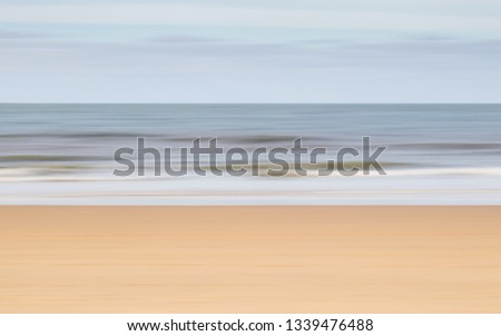 intentional camera movement to create a blurry landscape of the ocean and beach