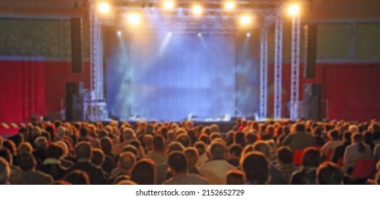intentionally blurred ideal as a backdrop with people spectators waiting for the start of the concert in the theater with the stage without any and customizable at will
