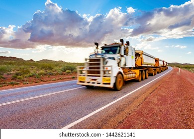 Intentionally blurred (in motion) road train with unbranded carriages on Australian outback highway. Pilbara mining region, Western Australia.