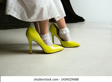 Interaction of children with adult world. Cute girl wearing mum's oversize shoes and dress for being older like she is. Little female model trying on clothes at home. Childhood, style, dream concept.