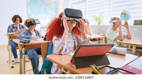 Interactive school concept. Kids in VR headsets sitting at desks and having virtual reality learning experience. Study technology. Kids in VR glasses in classroom. Tech education. - Powered by Shutterstock