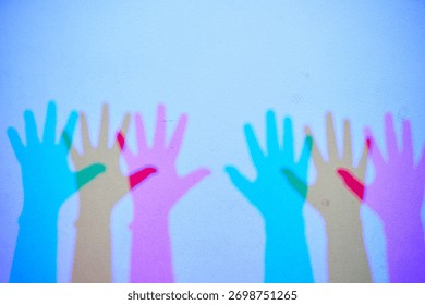 An interactive science exhibit demonstrating additive color mixing. The colorful shadows of hands are created by red, green, and blue lights.