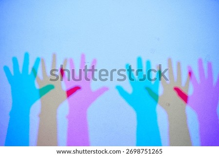 An interactive science exhibit demonstrating additive color mixing. The colorful shadows of hands are created by red, green, and blue lights.