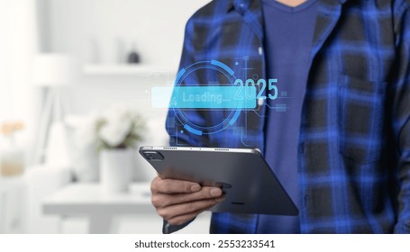 interacts with a tablet device displaying a futuristic loading interface symbolizing the transition between 2024 and 2025 showcasing technology evolution - Powered by Shutterstock