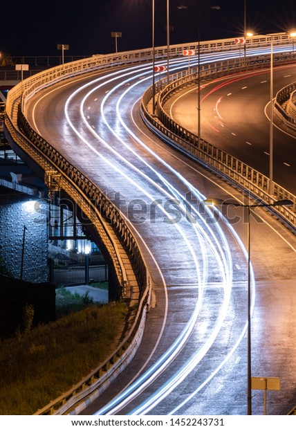 Interchange bridge road with\
car light streaks. Night light painting stripes. Long exposure\
photography.
