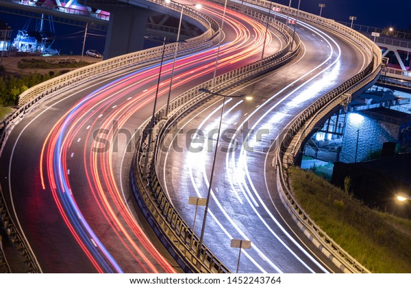 Interchange bridge road with\
car light streaks. Night light painting stripes. Long exposure\
photography.