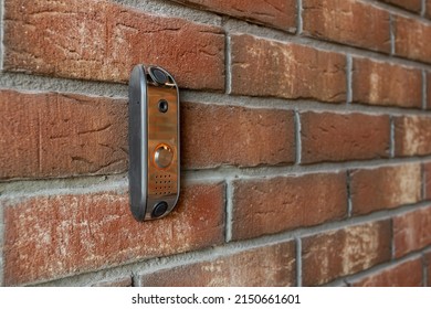 An intercom with a call button made of metal mounted on a brick wall
