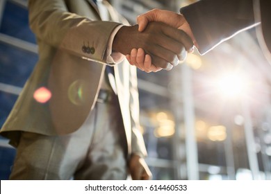 Intercultural traders handshaking after making deal