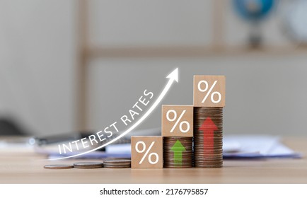 Interest on stacks of US dollars on a wooden table with an arrow pointing up. Finance and Mortgage Interest Rate Ideas wooden block with percentage icon and arrow pointing up the economy is improving - Shutterstock ID 2176795857
