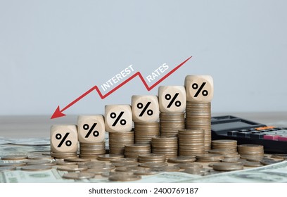 Interest rate decline, financial recession crisis, investment reduce, risk management concept. Wooden cube blocks with percentage sign and red down arrow with stack of coins. interest rates dropping.