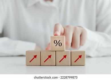 Interest rate finance and mortgage rates concept. Arrow up and hand touch on percentage sign on wooden block. financial growth, interest rate increase, inflation, sale price and tax rise concept.