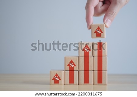 Interest rate finance and mortgage rates. Hand holding percentage sign on rise of arrow from ladder of wooden blocks, financial growth, interest rate increase, inflation, sale price, tax rise concept.