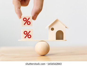 Interest rate financial and mortgage rates concept. Wooden home and hand putting cube block shape with icon percent on wood scales - Shutterstock ID 1656562843