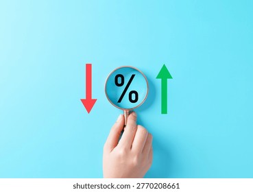 Interest rate increase and decrease concept. Magnifying glass over percentage symbol between red down and green up arrows representing finance analysis, rate change, inflation, loan cost, market trend