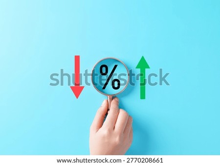 Interest rate increase and decrease concept. Magnifying glass over percentage symbol between red down and green up arrows representing finance analysis, rate change, inflation, loan cost, market trend