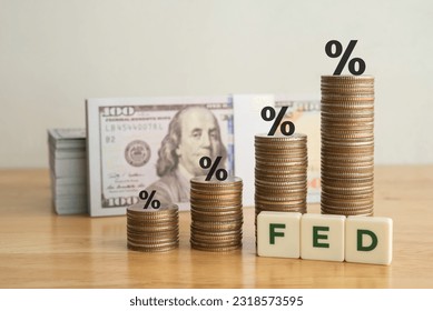 Interest rates on stack coins as graph chart growing up trend with FED letter and US dollar bill banknotes white wall background. FED fix great recession inflation crisis by increase interest rates. - Powered by Shutterstock