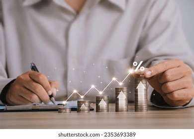 Interest rates,Inflation and tax concept.Businessman putting coins stacking with up arrow and a percentage sign increase in investment and interest rates.Financial graphical and statistical analysis. 