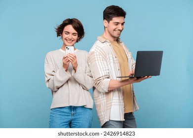 Interested couple looking at smartphone and laptop isolated on blue background. Happy friends holding digital devices, working online. Technology, social media addiction concept  - Powered by Shutterstock