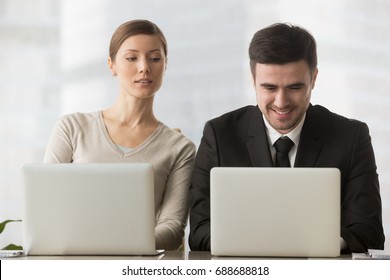 Interested curious corporate spy looking at colleagues laptop, spying on rival, cheating on examination, stealing idea, sneaking peek, taking inquisitive glance at computer screen of unaware coworker - Shutterstock ID 688688818