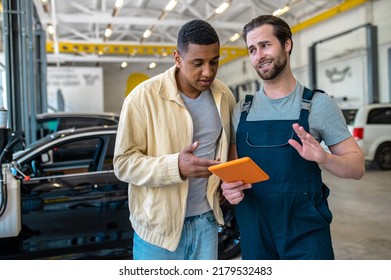 Interested Customer Looking At Tablet And Mechanic Confident