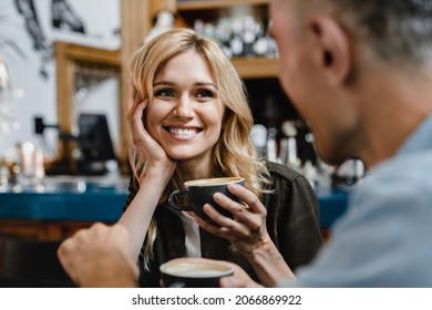 Interested excited falling in love mature woman listening to her husband man boyfriend while drinking coffee in restaurant cafe on a date - Shutterstock ID 2066869922