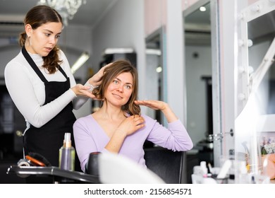 Interested Female Client Sitting In Chair While Discussing Haircut With Positive Girl Professional Hairdresser ..