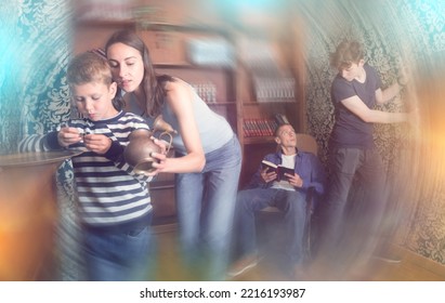 Interested Focused Young Family With Two Tween Boys Looking For Clue In Quest Room. Toned Image With Radial Blur Effect