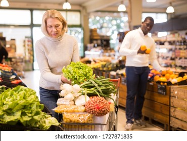 Interessierte reife Weibchen kaufen im Lebensmittelgeschäft, auf der Suche nach frischem Gemüse