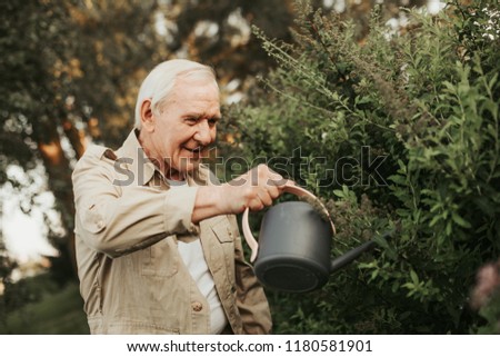 Interested old female person pouring shrub and looking at it with kind smile. Waist up portrait. Copy space on right side