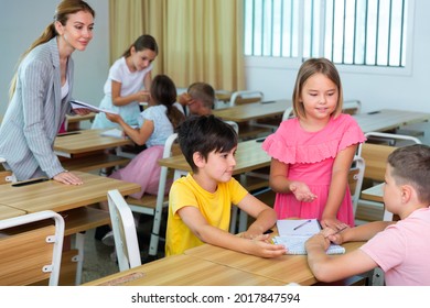 Interested Preteen Pupils Divided Into Small Groups, Discussing Learning Material In Classroom. Group Work As Effective Teaching Method