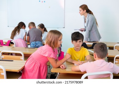 Interested Preteen Pupils Divided Into Small Groups, Discussing Learning Material In Classroom. Group Work As Effective Teaching Method