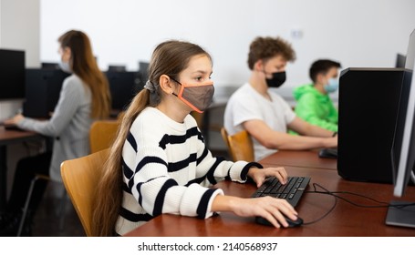 Interested Teen Girl In Protective Face Mask Studying With Classmates In School Computer Class. Necessary Pandemic Precautions..