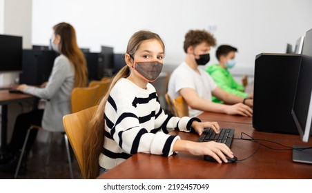 Interested Teen Girl In Protective Face Mask Studying With Classmates In School Computer Class. Necessary Pandemic Precautions..