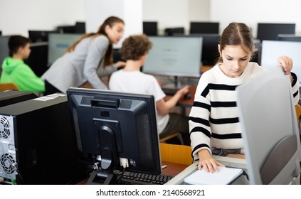 Interested Teen Girl Student Copying Notes From Workbook On Copier While Studying In College Computer Class..