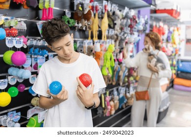 Interested teenage boy choosing funny safe toys for four-legged friend in pet shop - Powered by Shutterstock