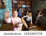 Interested tween girl trying to reach for some item in escape room stylized as old library, holding out her hand .