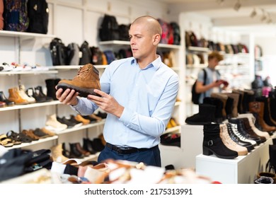 Interested Young Man Looking For Comfortable Demi-season Mens Shoes In Modern Shoe Store.