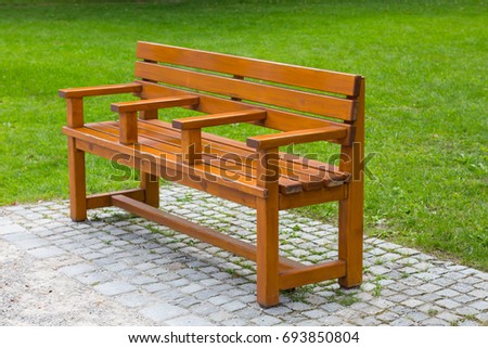 Interestin unusual wooden park bench at a park, divided on three part